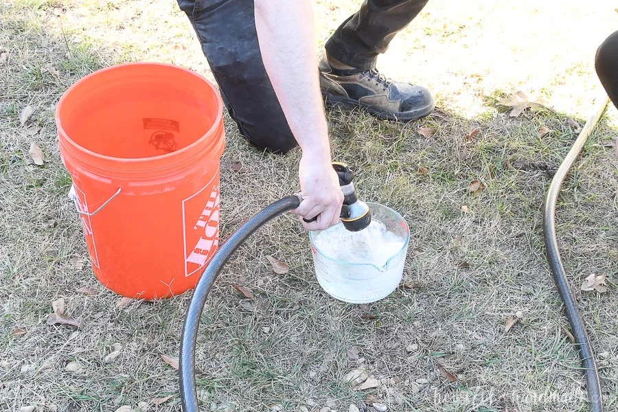 Measuring water from a hose into a pyrex measuring cup next to a 5 gallon bucket. 