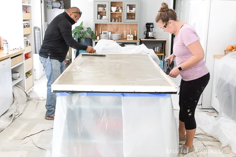 One person moving the cement into the edges of the form while the other vibrates the edges with an electronic sander. 