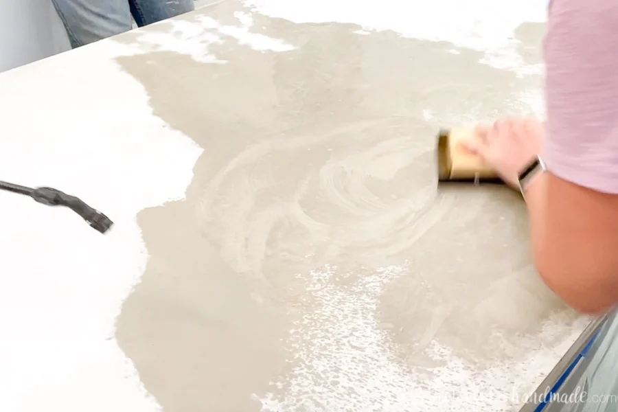 Hand sanding the top of the concrete countertop with a wet sandpaper on a block of wood. 