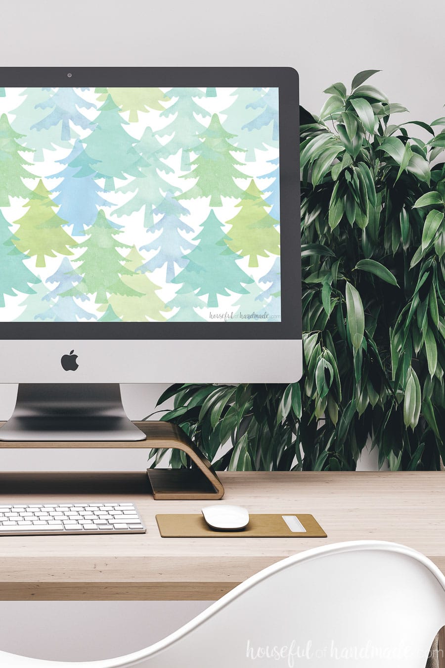 Watercolor evergreen trees in tones of greens and blues in an allover pattern as the December digital wallpaper on a computer screen. 