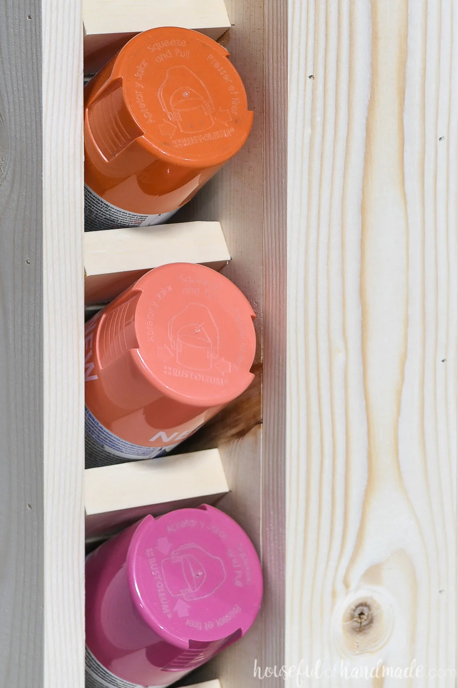 Close up of three paint cans in the slots of the spray paint storage. 