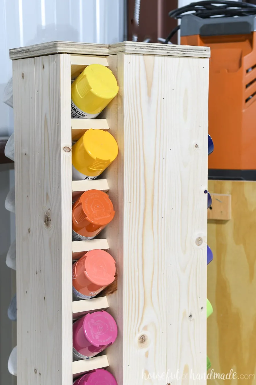 Close up of the top of the storage cabinet with yellow, orange and red spray paint in the slots. 