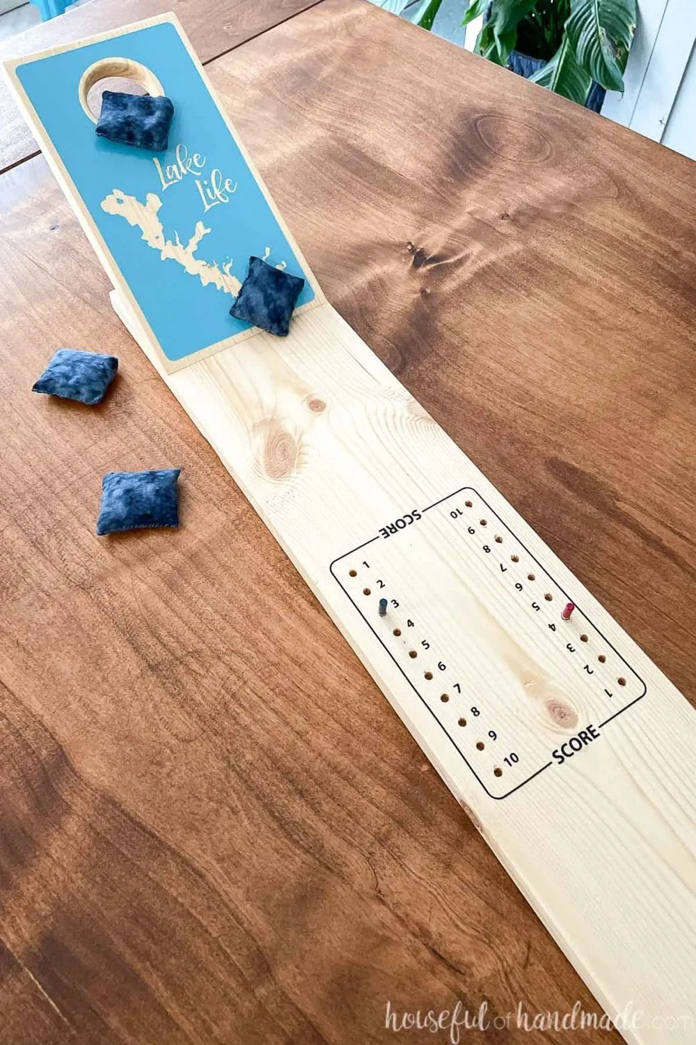 Close up view of the center of the tabletop cornhole game with a peg style scoreboard in the center. 