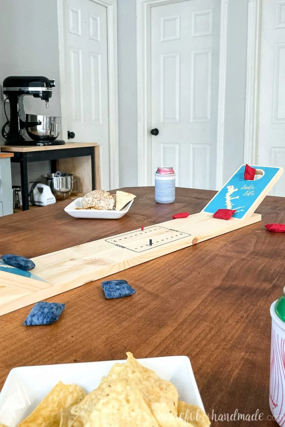Looking across a dining table set for game night with snacks and a DIY tabletop cornhole game in the center. 