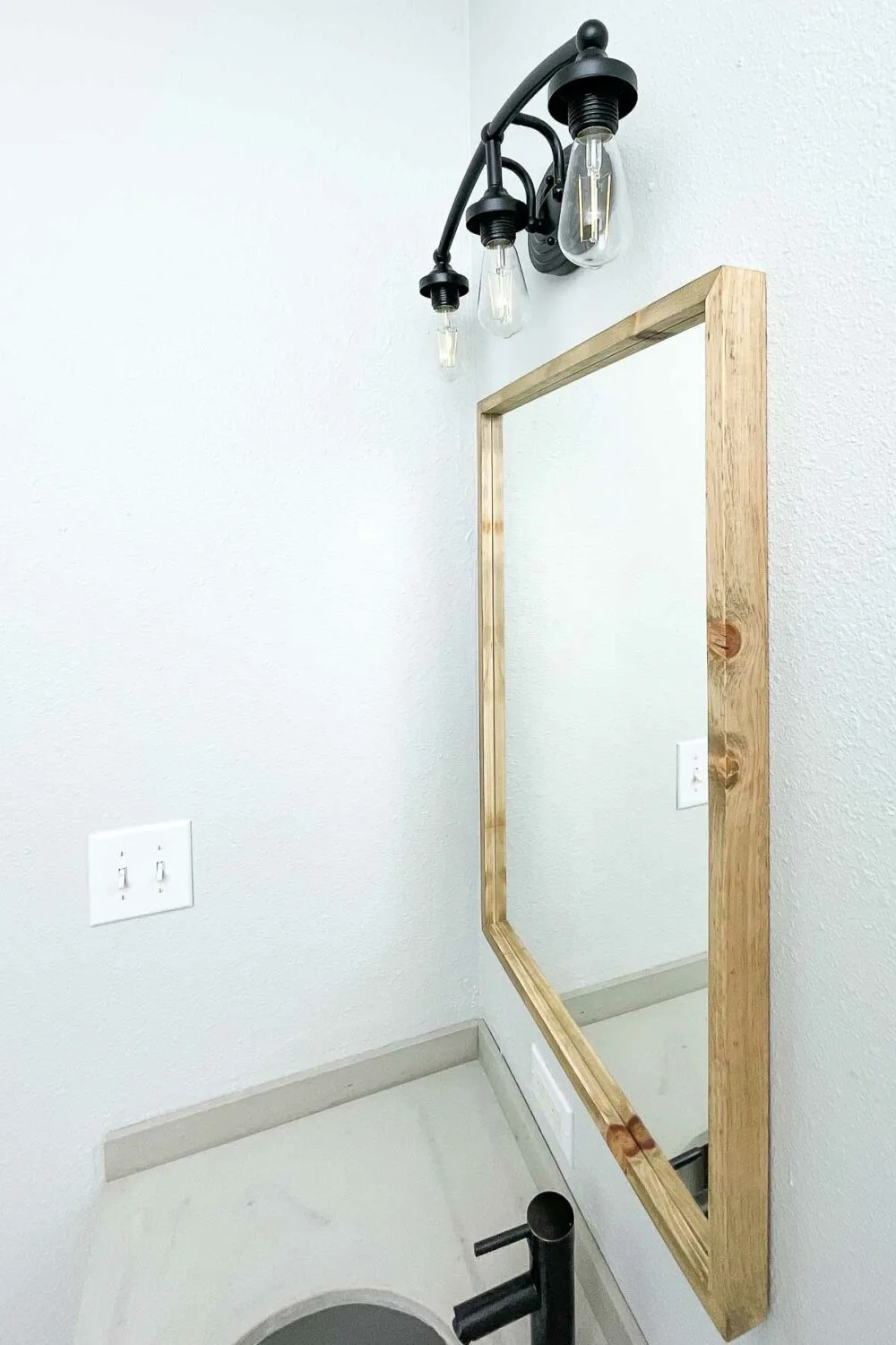 Looking at the side of the mirror in the bathroom on the light gray walls. 