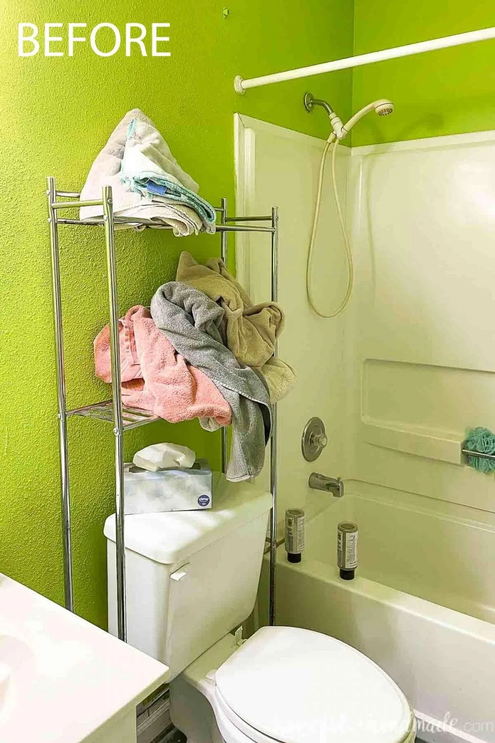 Picture of the green walls and metal shelving with poorly folded towels over the toilet. 
