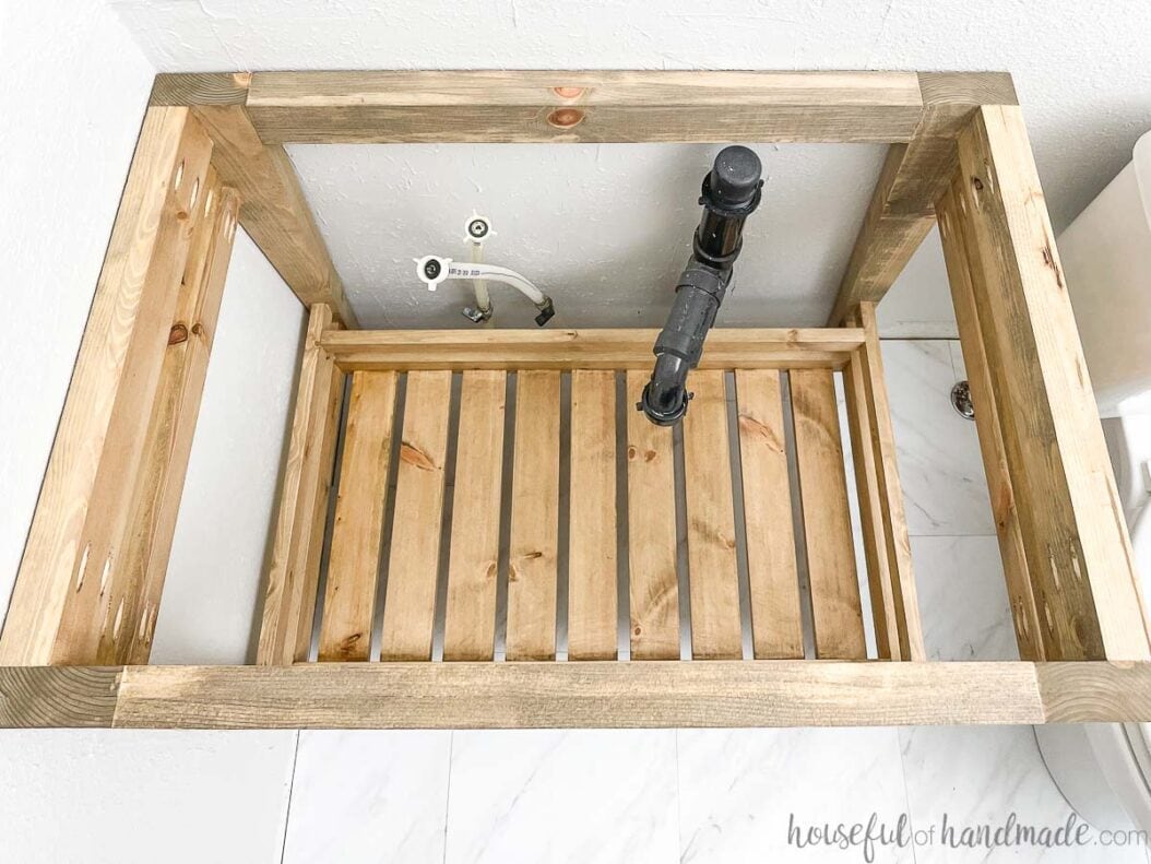 Top down view of the open bathroom vanity with lower shelf made from left over wood. 