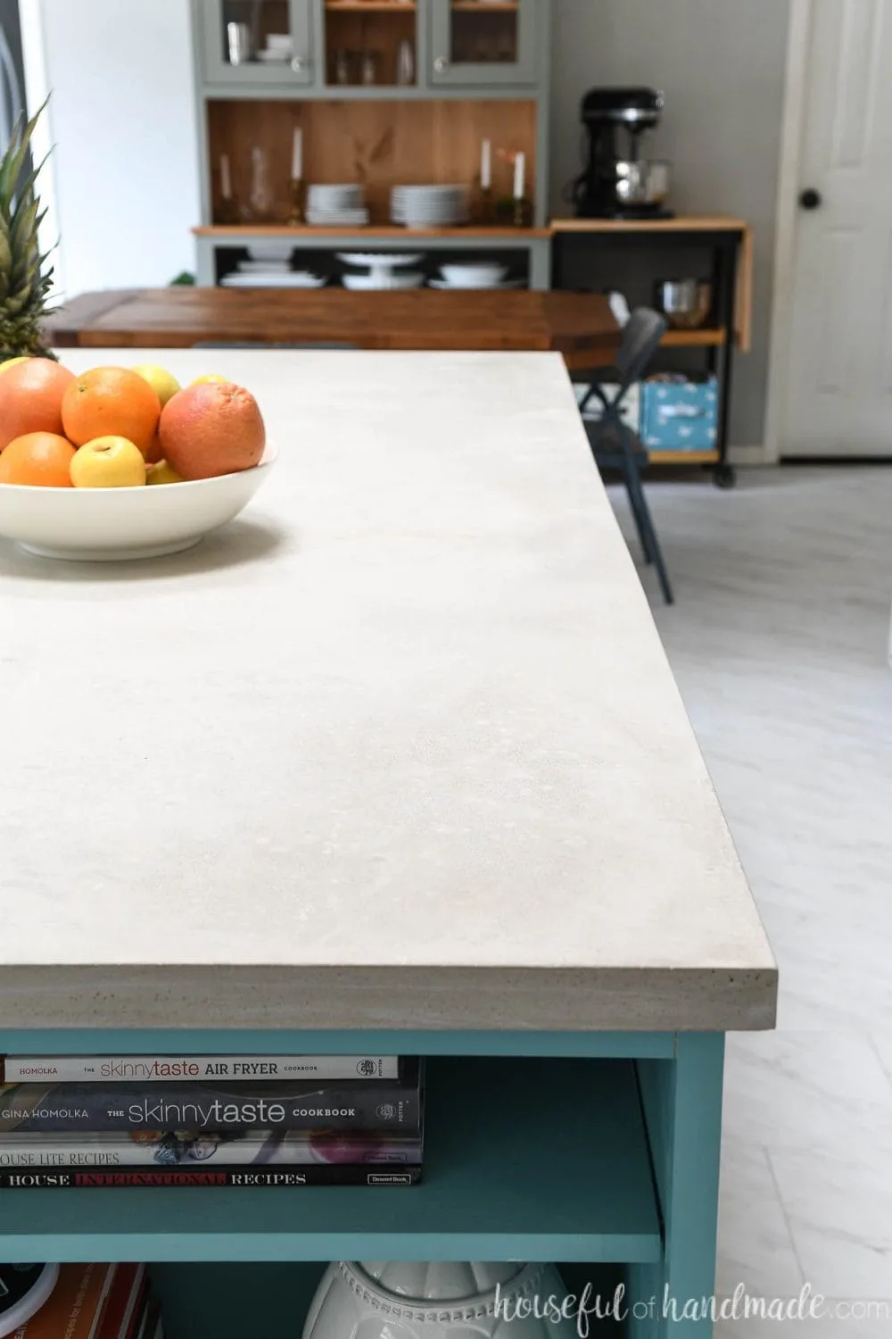 Kitchen island painted with an soft turquoise color and a DIY concrete countertop with bowl of fruit on the countertop.