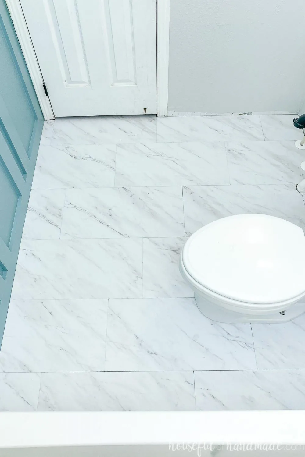 Looking at the floor in the bathroom remodel with vinyl tiles and the board and batten wall on one side.