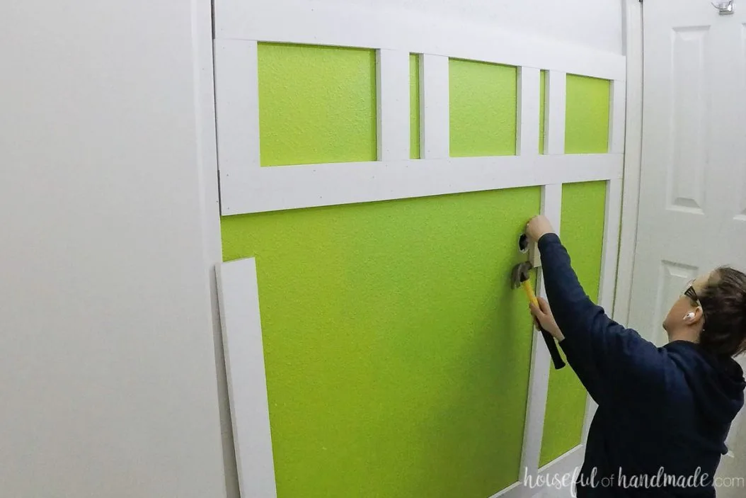 Tapping the boards into place with a scrap of wood and a hammer. 