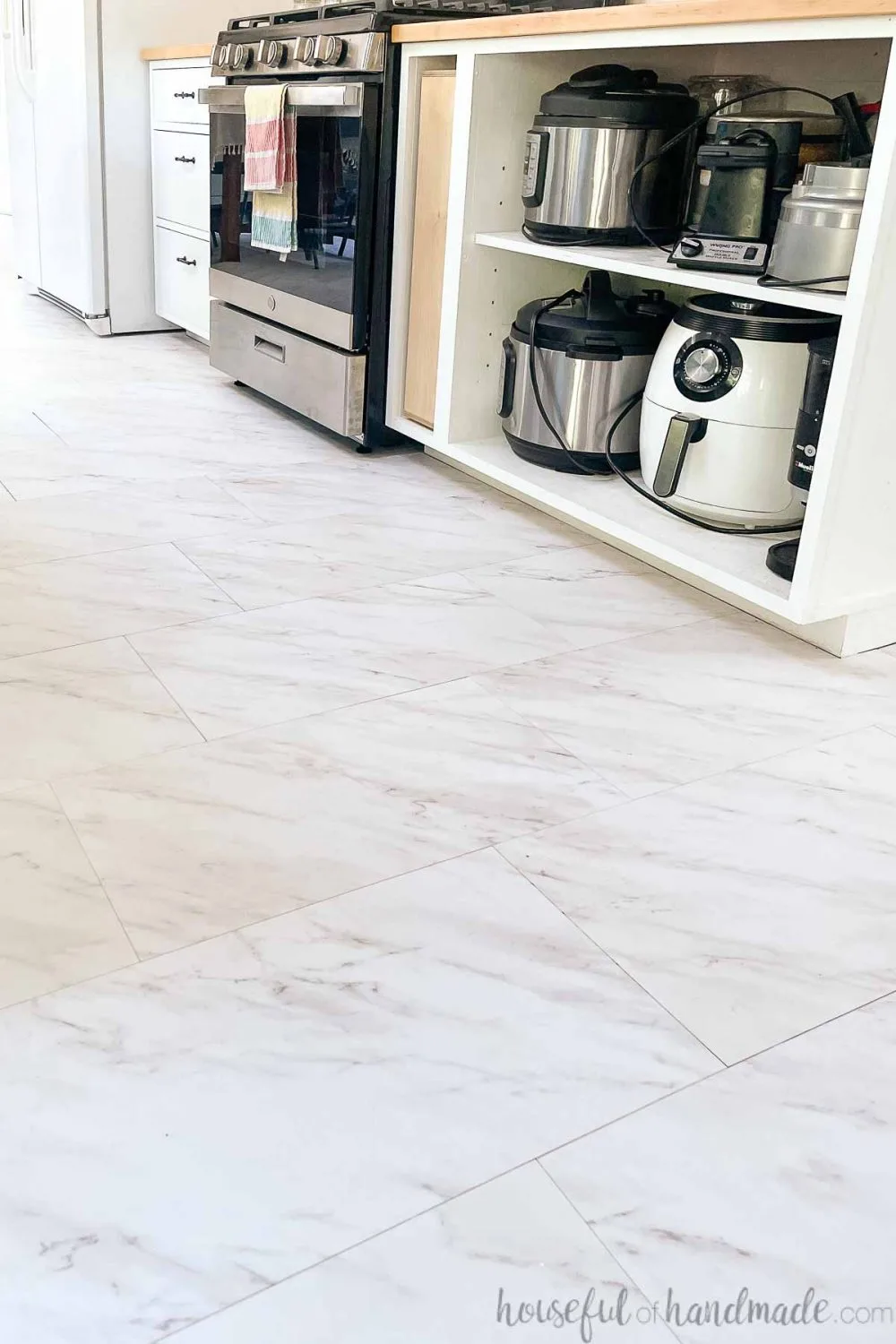 Peel and stick vinyl tiles that look like white marble with gray veining on the floor in a DIY kitchen.