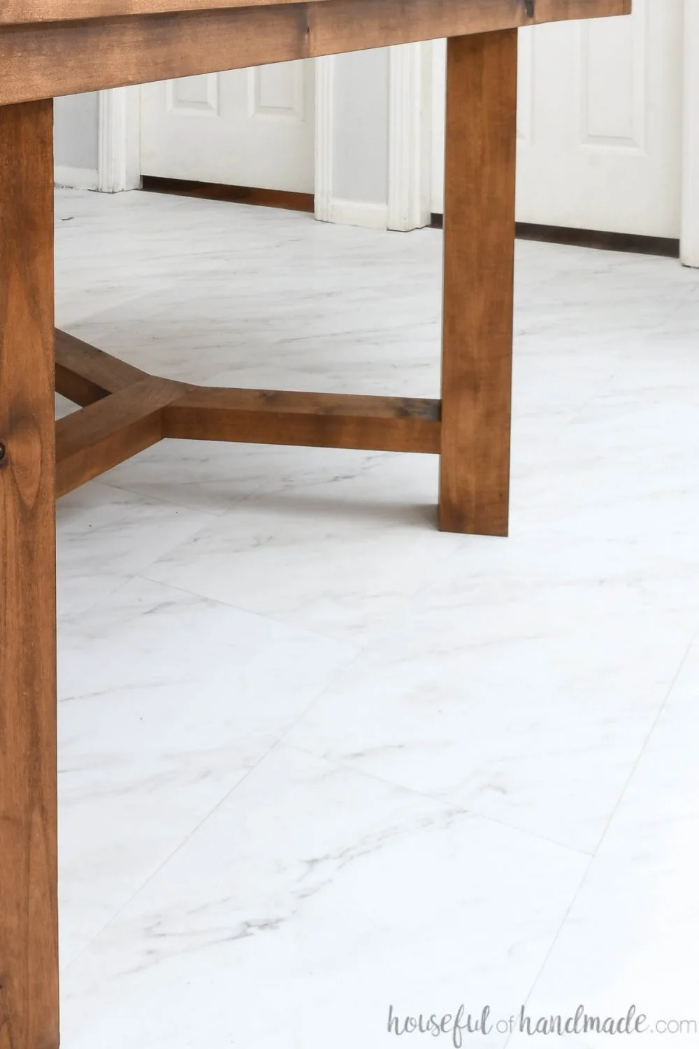 Close up of the grecian marble look vinyl tile installed in the dining room under a rustic table. 