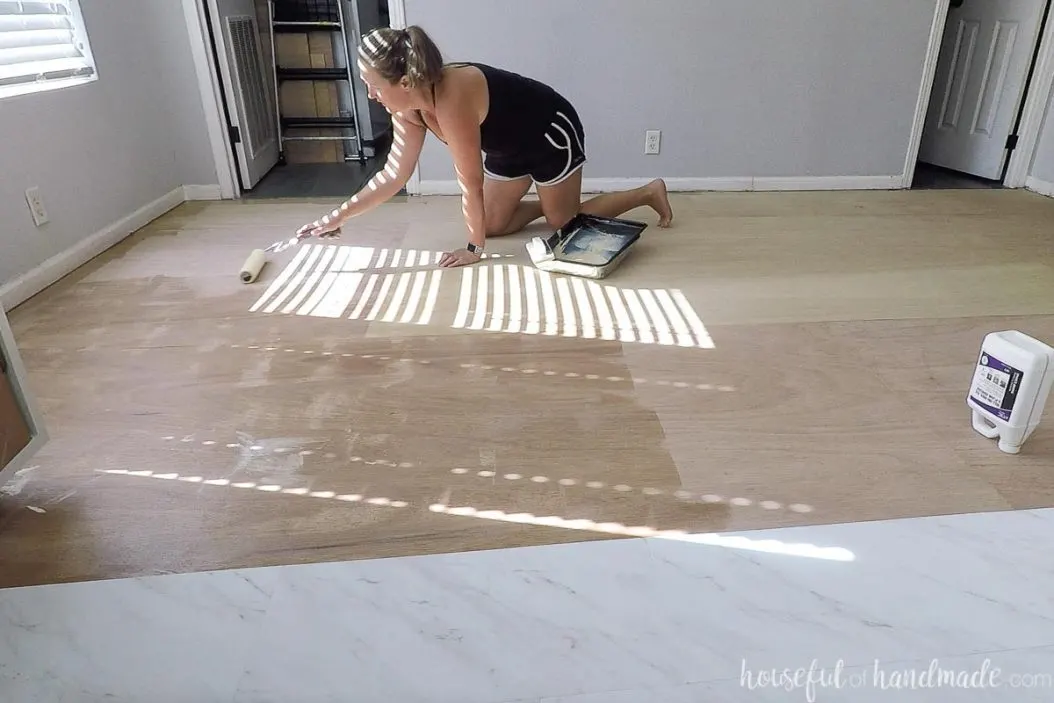 Applying roll on vinyl tile adhesive with a paint roller.