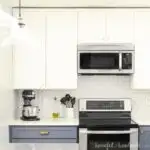 Kitchen with full height white kitchen wall cabinets and soft navy blue base cabinets.