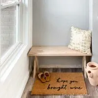 DIY x-leg bench made from hickory wood in an entryway with driftwood vinyl flooring and 