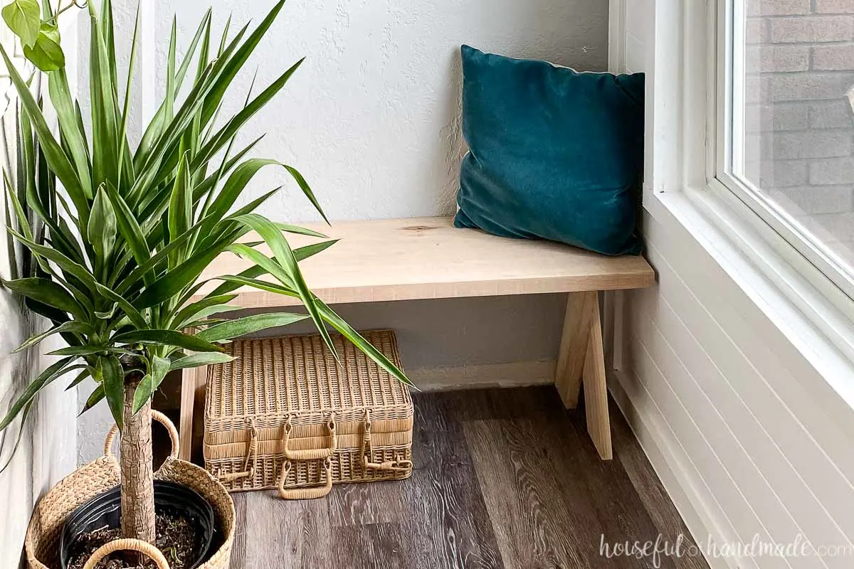 Horizontal photo of the bench in the entryway with a plant and accessories around it. 