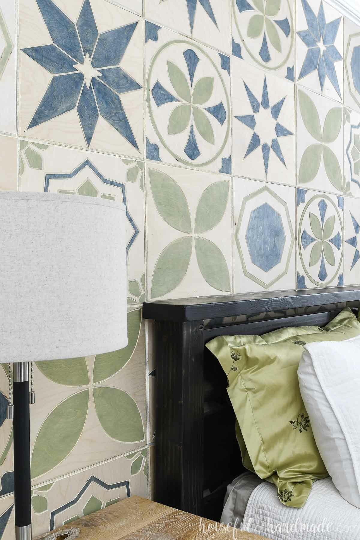 Angled view of the patterned tile DIY accent wall installed on the wall behind a bed. 