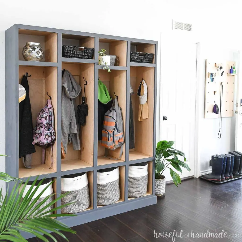 DIY storage cabinet with 4 locker sections for storing coats, shoes, backpacks, and more in a room with white walls and dark wood floors. 