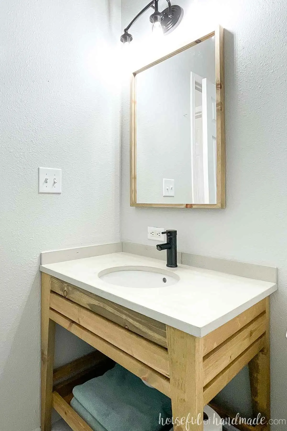 Corner view of the budget bathroom vanity remodel showing the DIY concrete vanity top on the open wood vanity. 