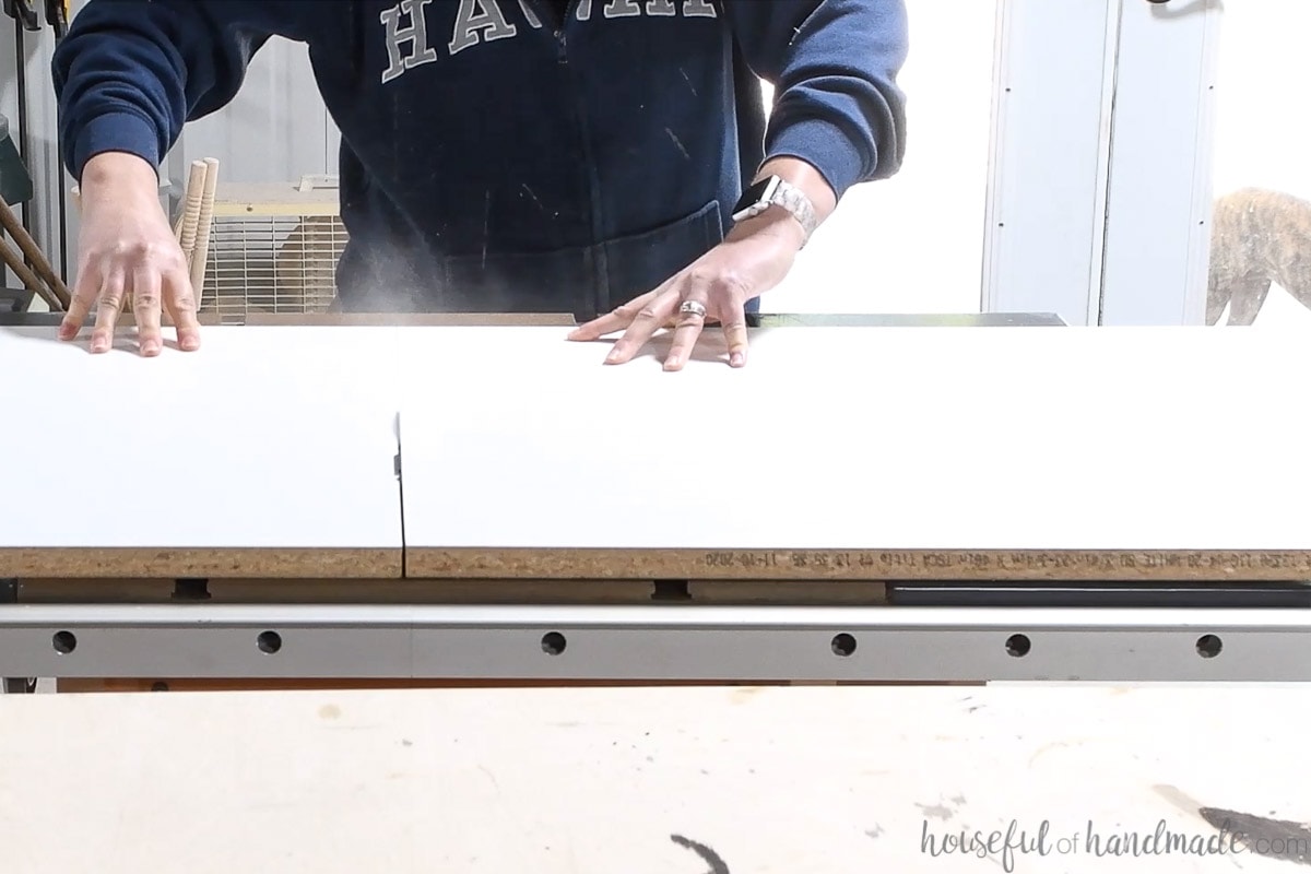 Cutting melamine covered shelf board on a table saw.