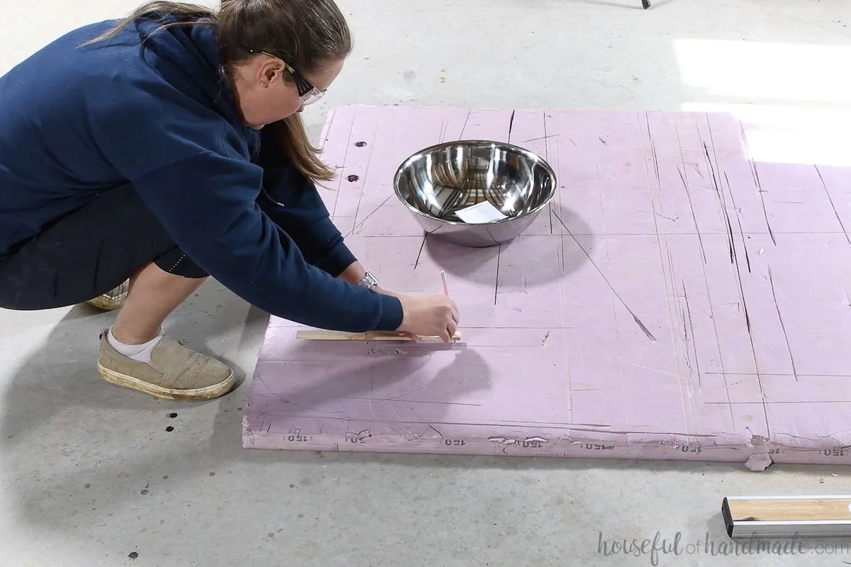 Drawing a circle on a piece of pink rigid foam with a jig. 