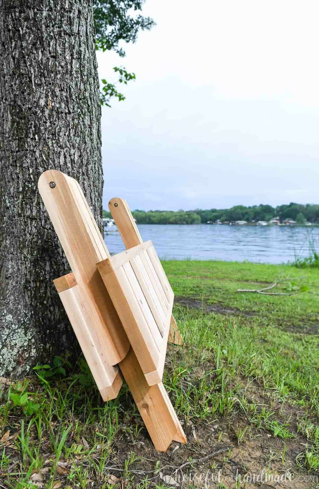 Outdoor folding picnic table folded down leaning up against a tree. 