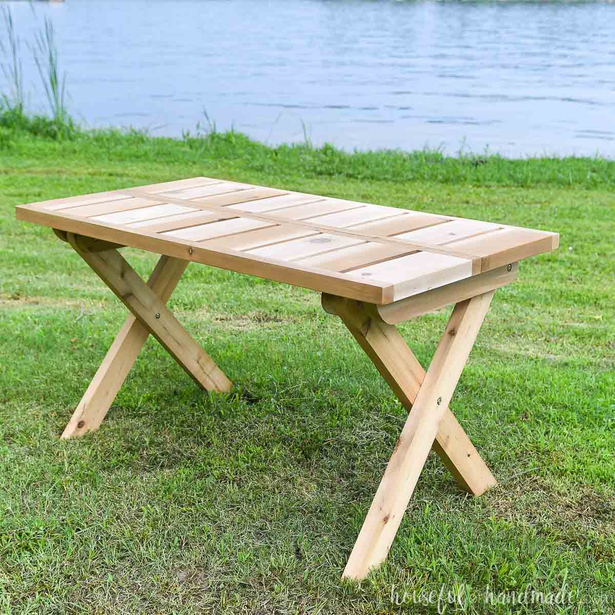 Wooden folding picnic table set up outside on the grass.