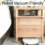 Picture of a white robot vacuum cleaning under a nightstand with text overlay: 11 Furniture Builds that are Robot Vacuum Friendly.