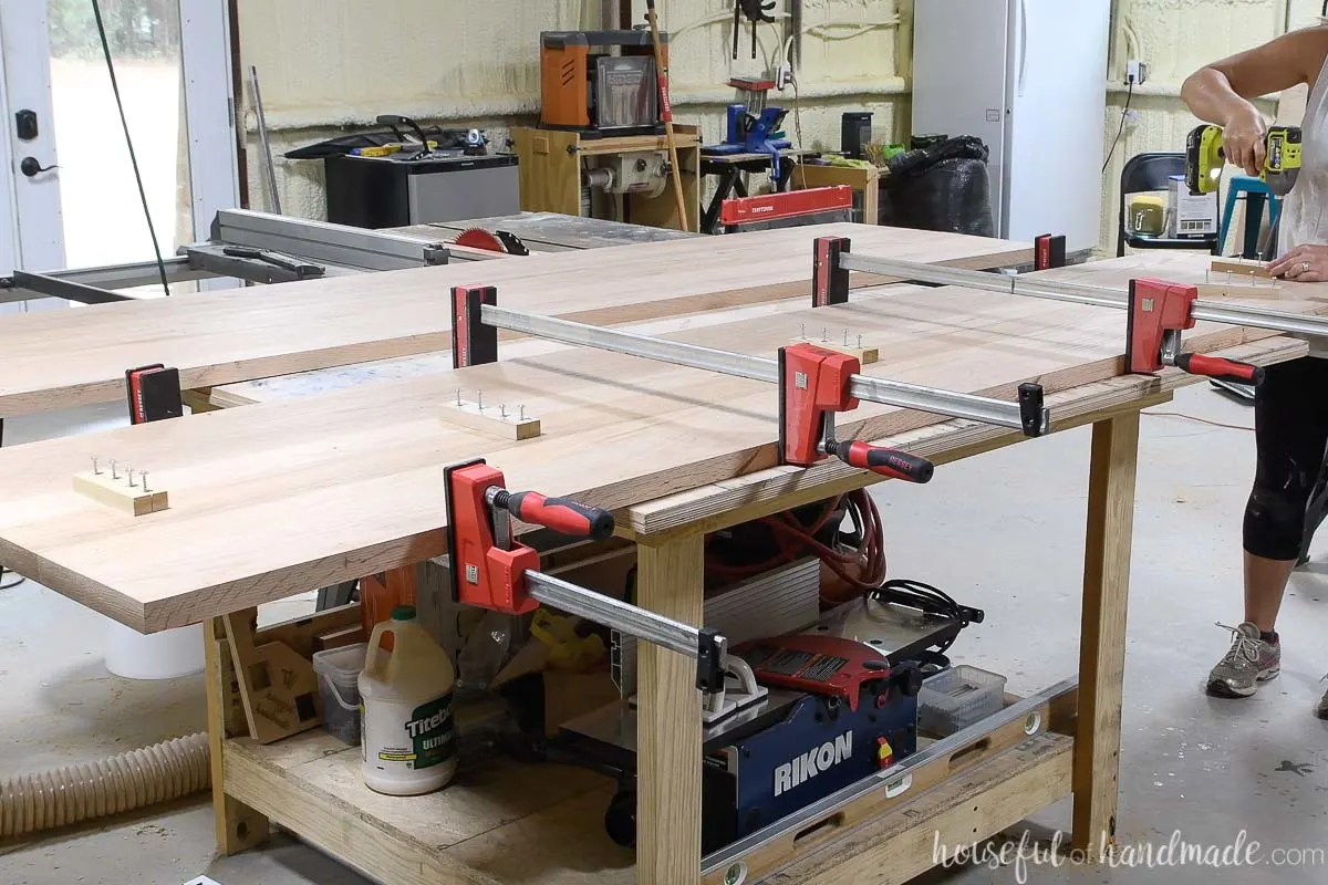 Two boards clamped together on a table with scraps of wood attached to the seams to hold them together. 