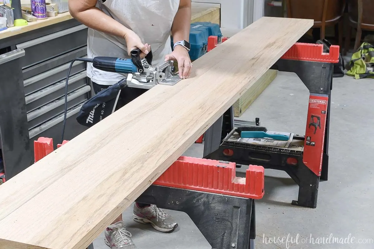 Adding biscuit slots to the table top board sitting on a sawhorse. 