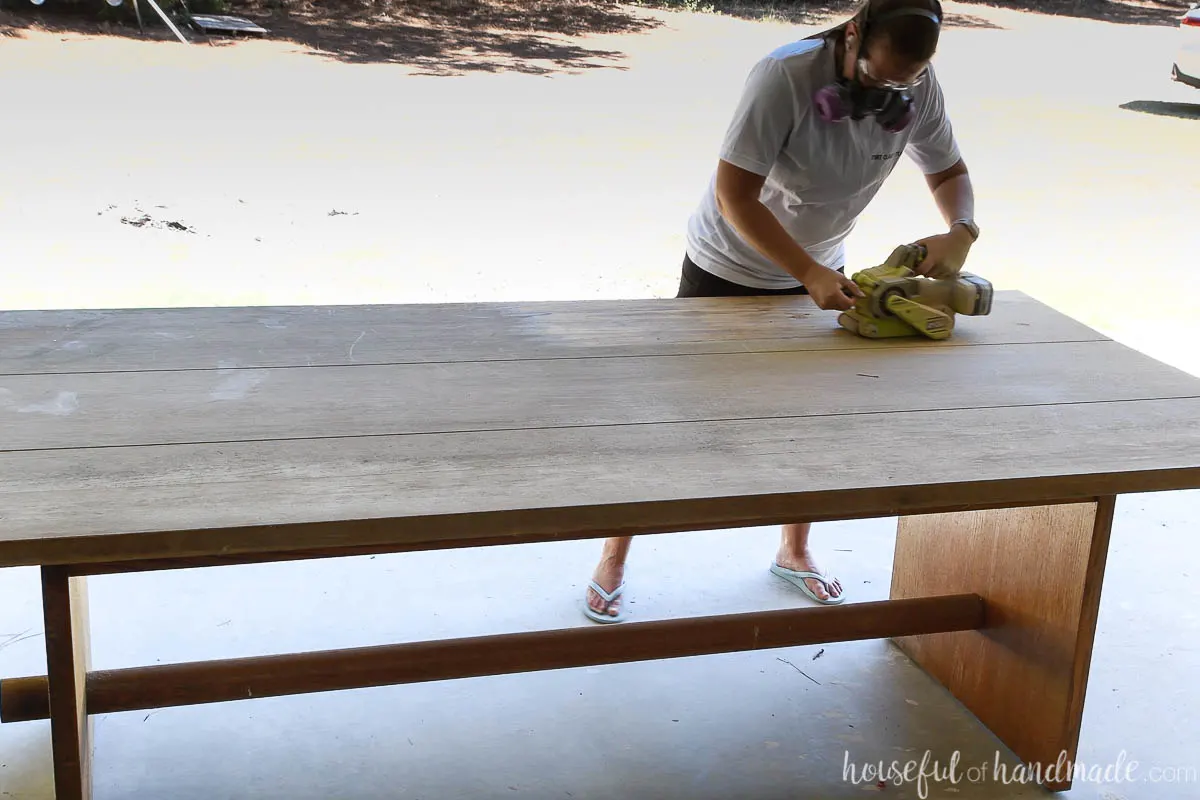 Sanding the top of an old oak table with a belt sander.
