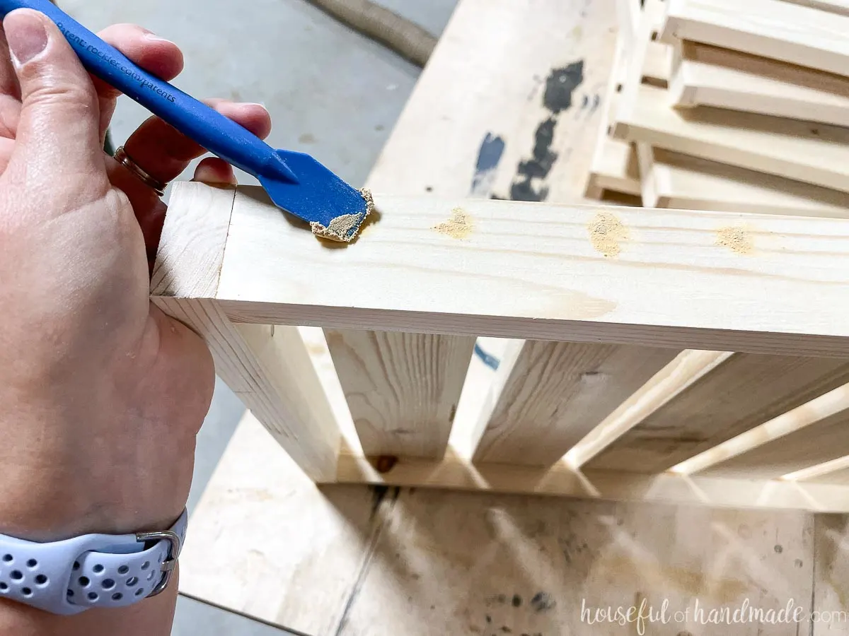 Filling the nail holds on the sides of the assembled shelves with stainable wood putty. 