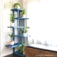 Multi-tier corner plant stand with room for more that 6 plants in a corner next to a window.