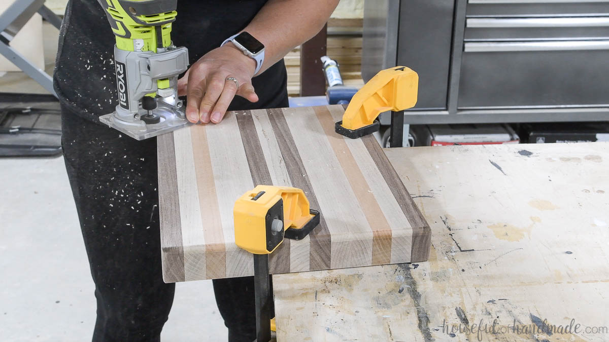 Using a trim router to add a round over edge to the hardwood cutting board. 