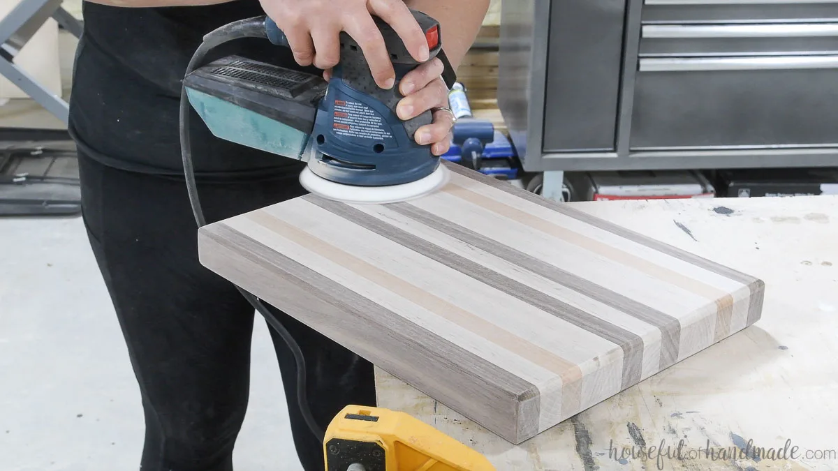 Sanding the cutting board smooth to 220 grit sandpaper with an orbital sander. 