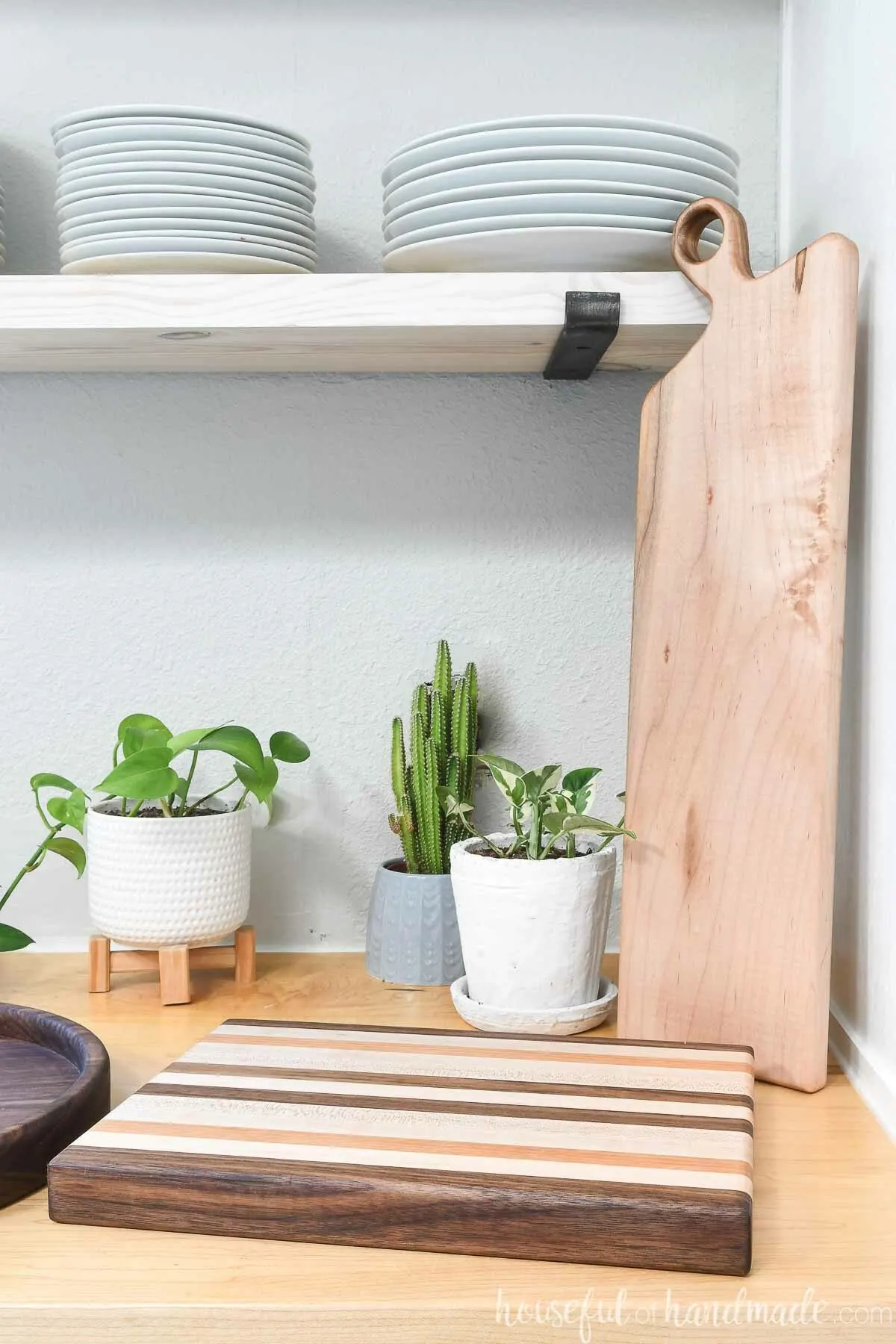 Kitchen with 3 handmade woodworking gifts on the counter under open shelves. 