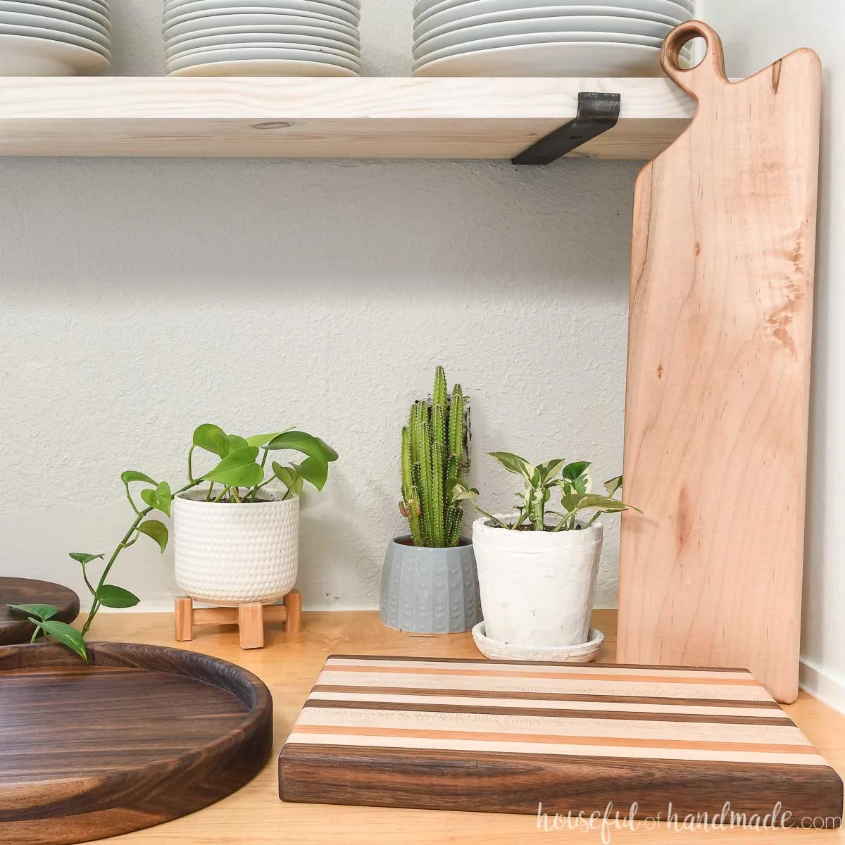 3 easy woodworking gifts: a charcuterie board, round serving tray, and edge grain cutting board, in a kitchen.