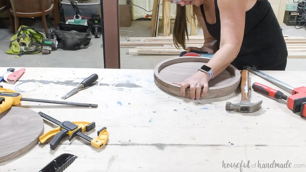 Sanding the outside edge of the DIY round tray with an orbital sander. 