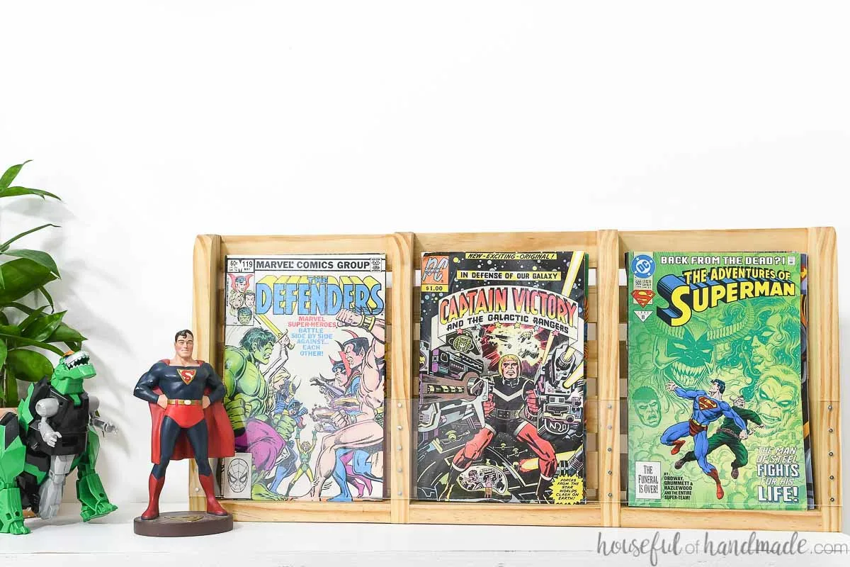 Triple comic book storage shelf filled with up to 60 comic books on a shelf next to toys. 