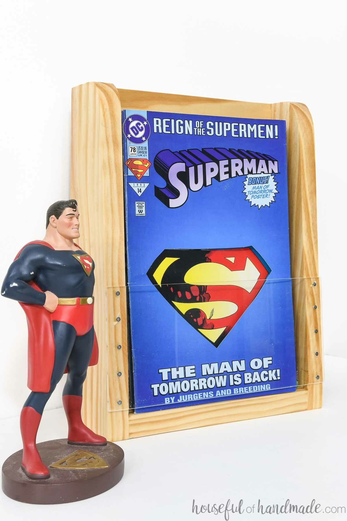Superman comic book in a comic book display shelf next to a superman figure. 