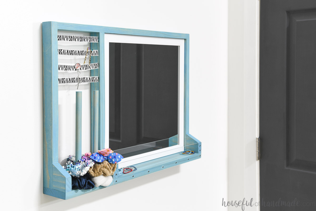 Hair accessory storage with a mirror hanging on a wall. 