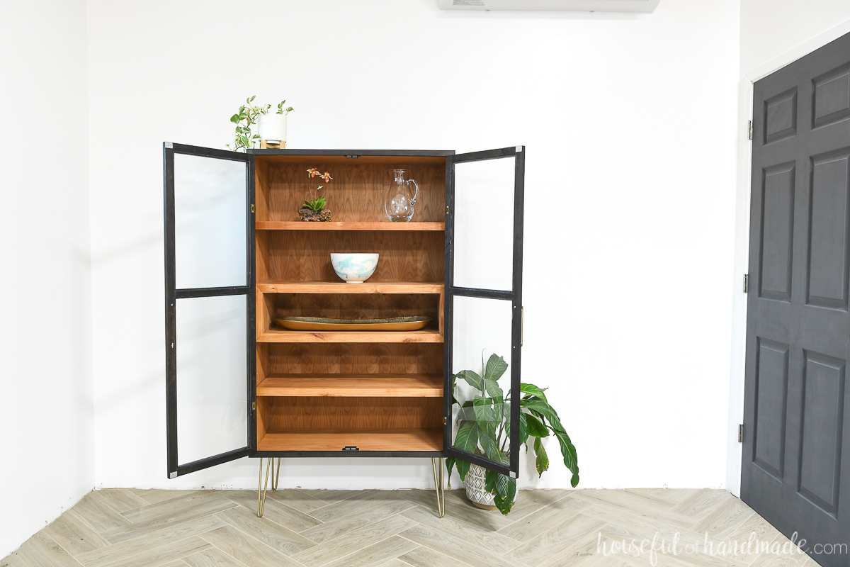 DIY display cabinet with glass doors open showing the stained wood inside.