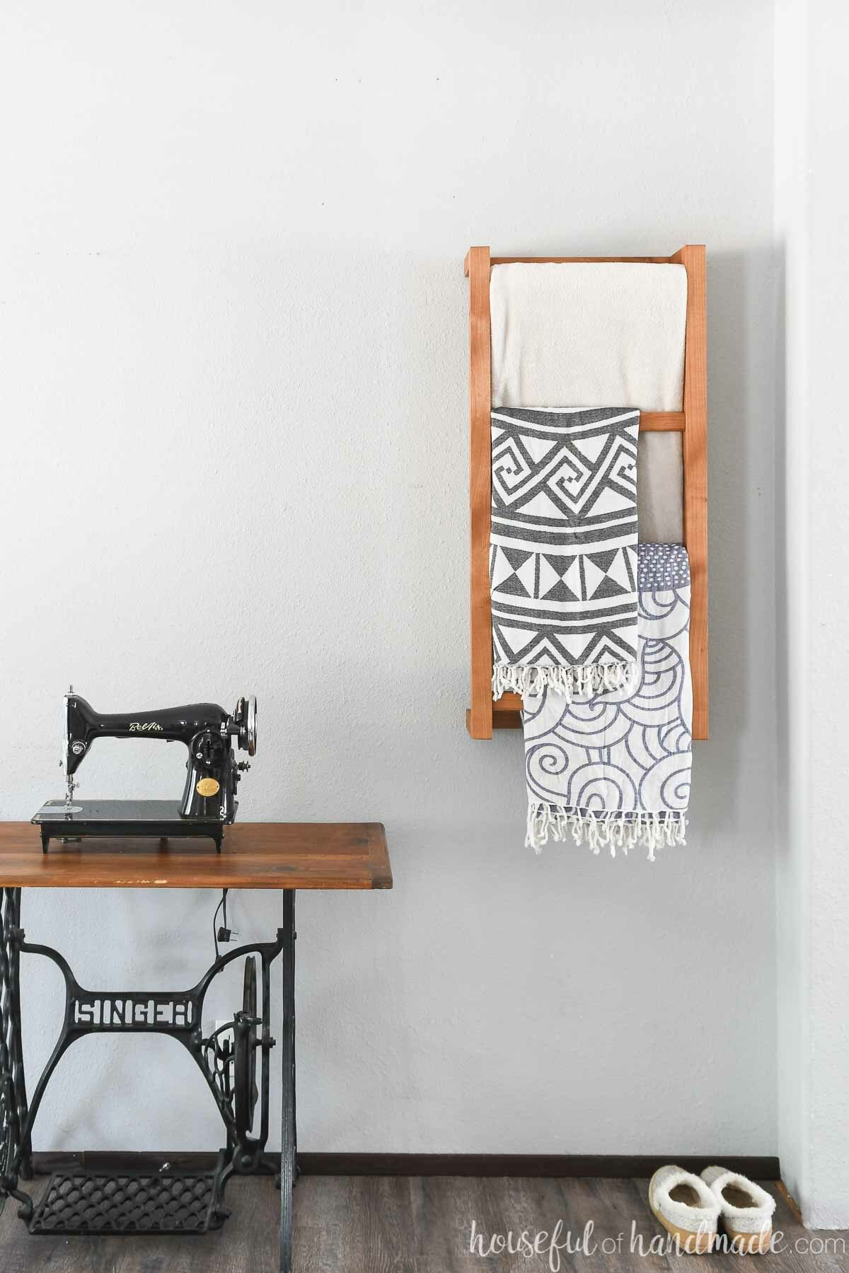Wall mounted ladder for blankets or towels on a wall in a bedroom with throws on it. 