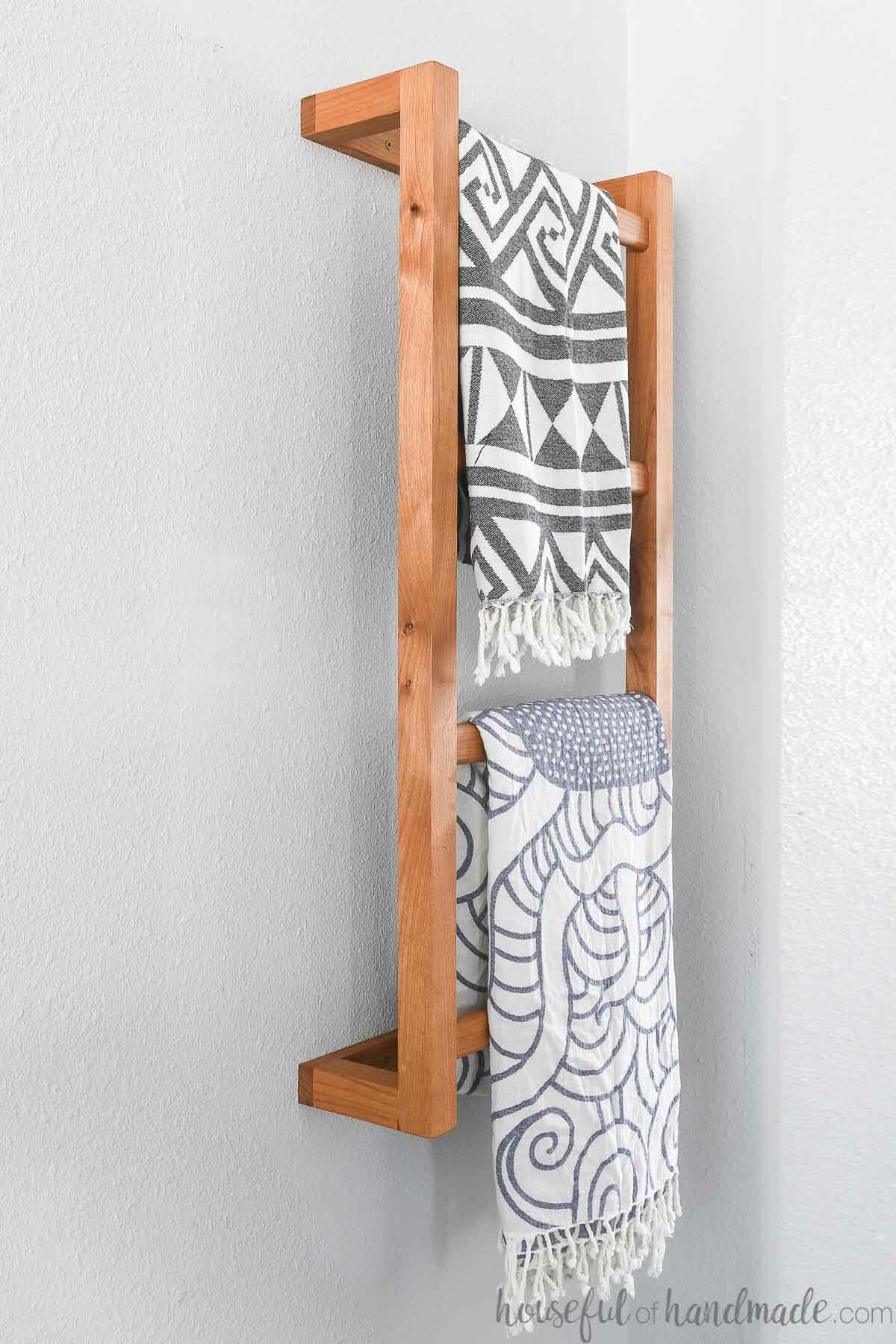 Close up of the wall mounted wooden ladder with 2 blankets on it. 