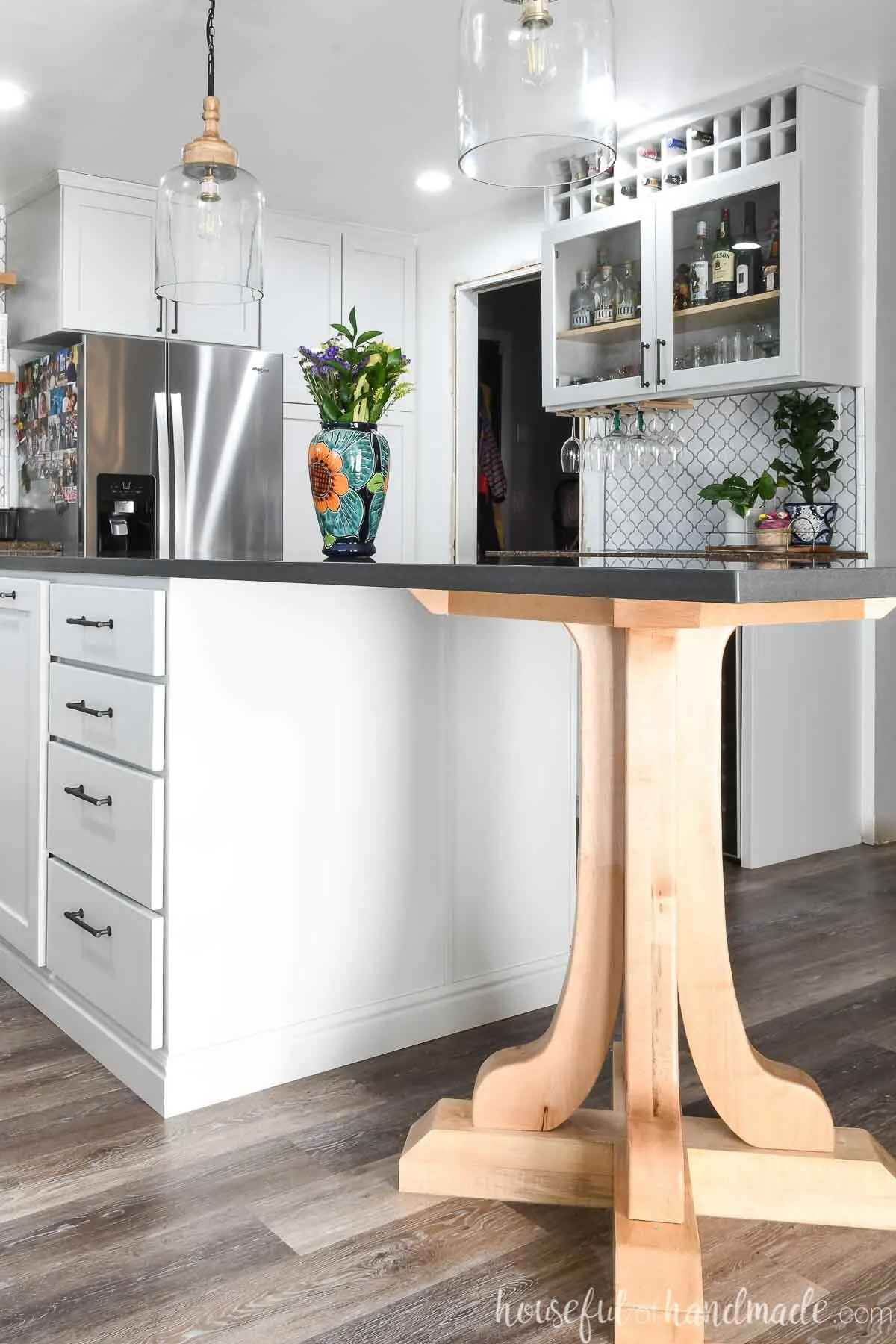 Black quartz topped kitchen island with a large maple pedestal on one end for bar height seating.