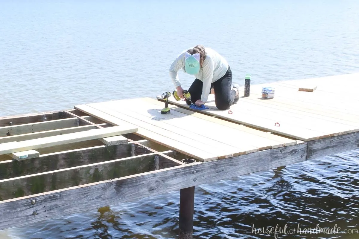 Girl attaching new deck boards on a dock.