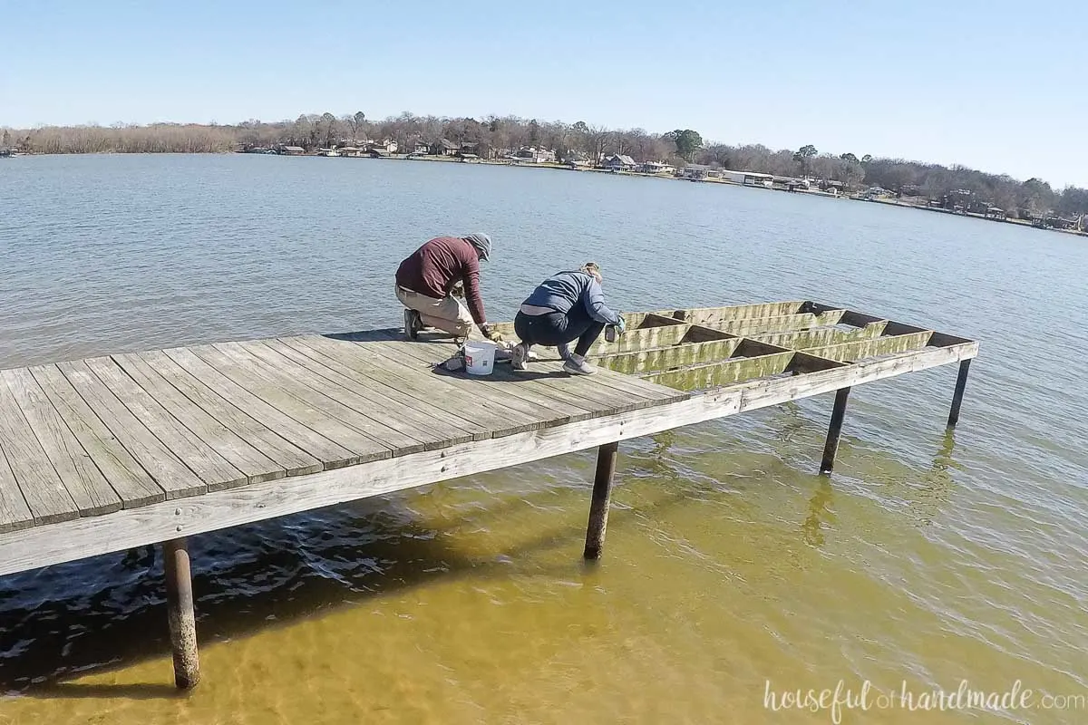 Two people removing the old deck boards from the dock. 