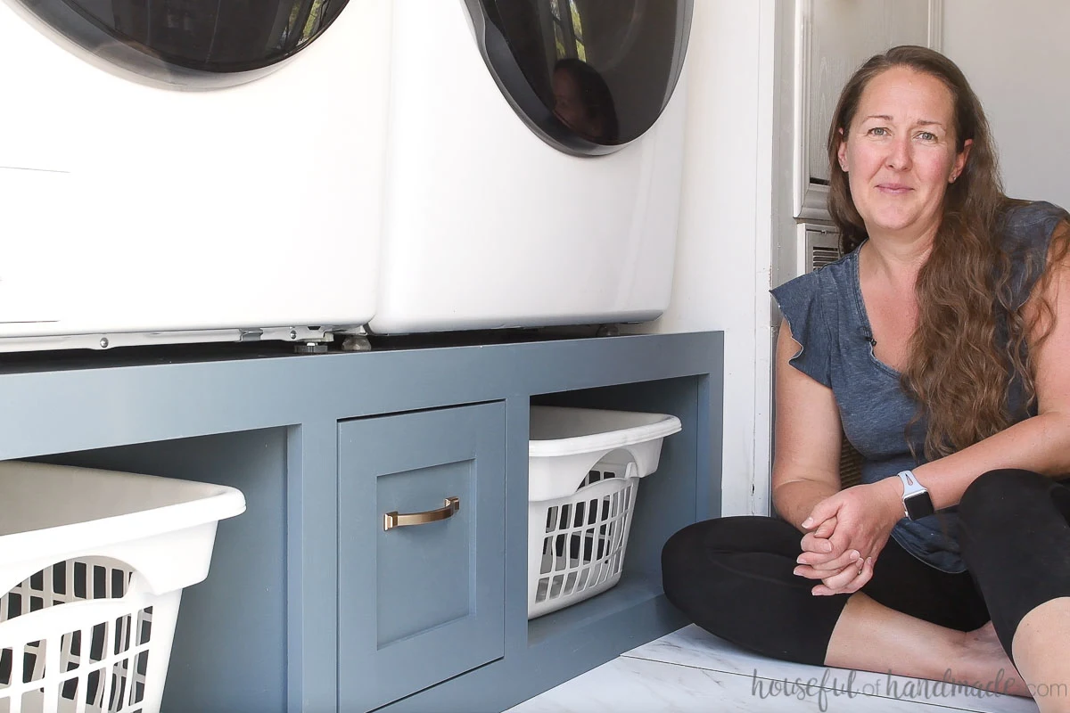 Kati from Houseful of Handmade sitting next to the completed DIY washer and dryer platform. 