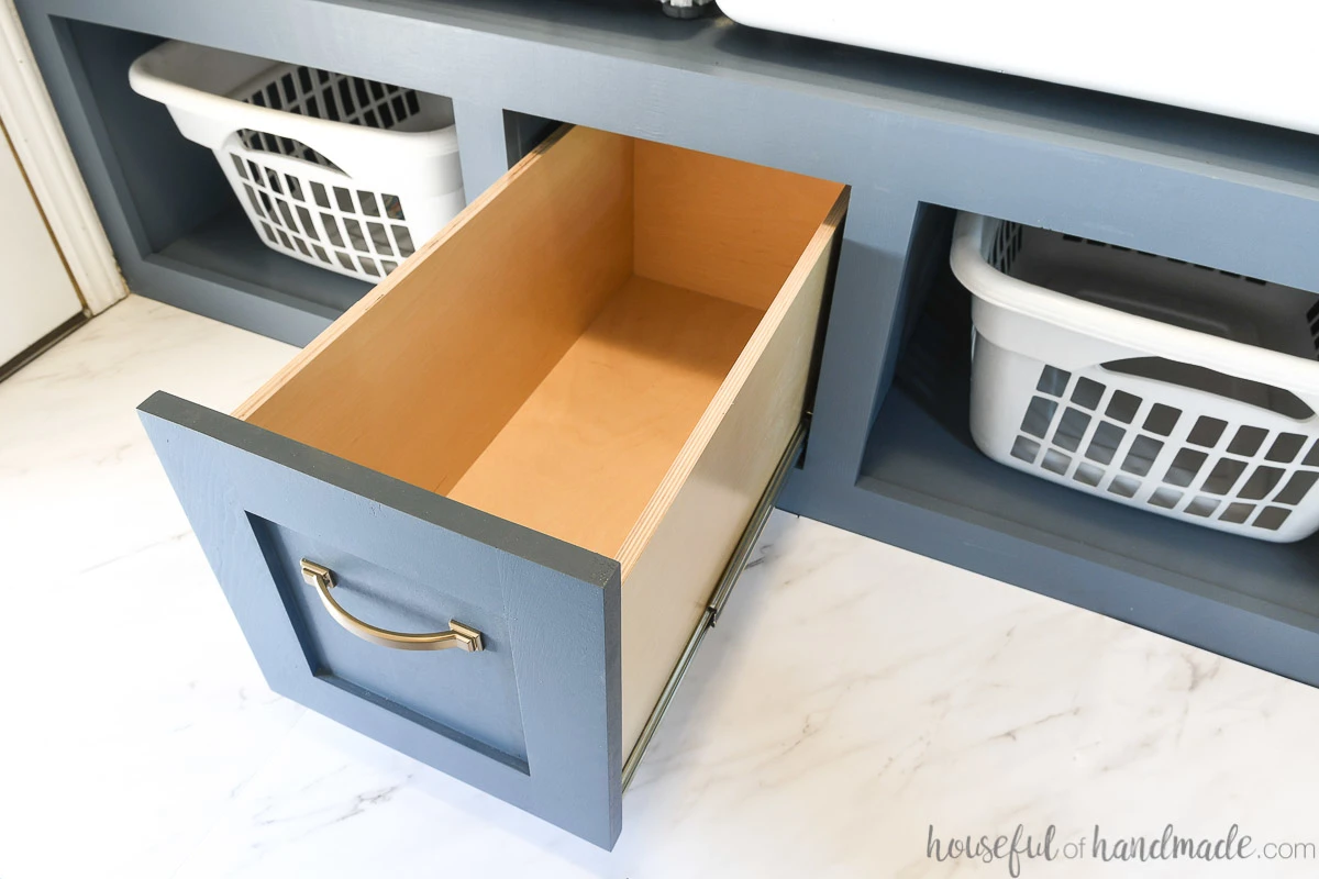 Large drawer in the center of the washer and dryer platform opened up looking inside it.