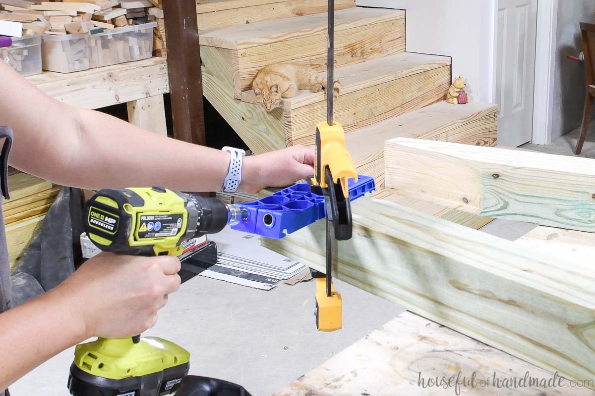 Drilling a pocket hole in the 4x4 board with the Kreg pocket hole XL jig. 